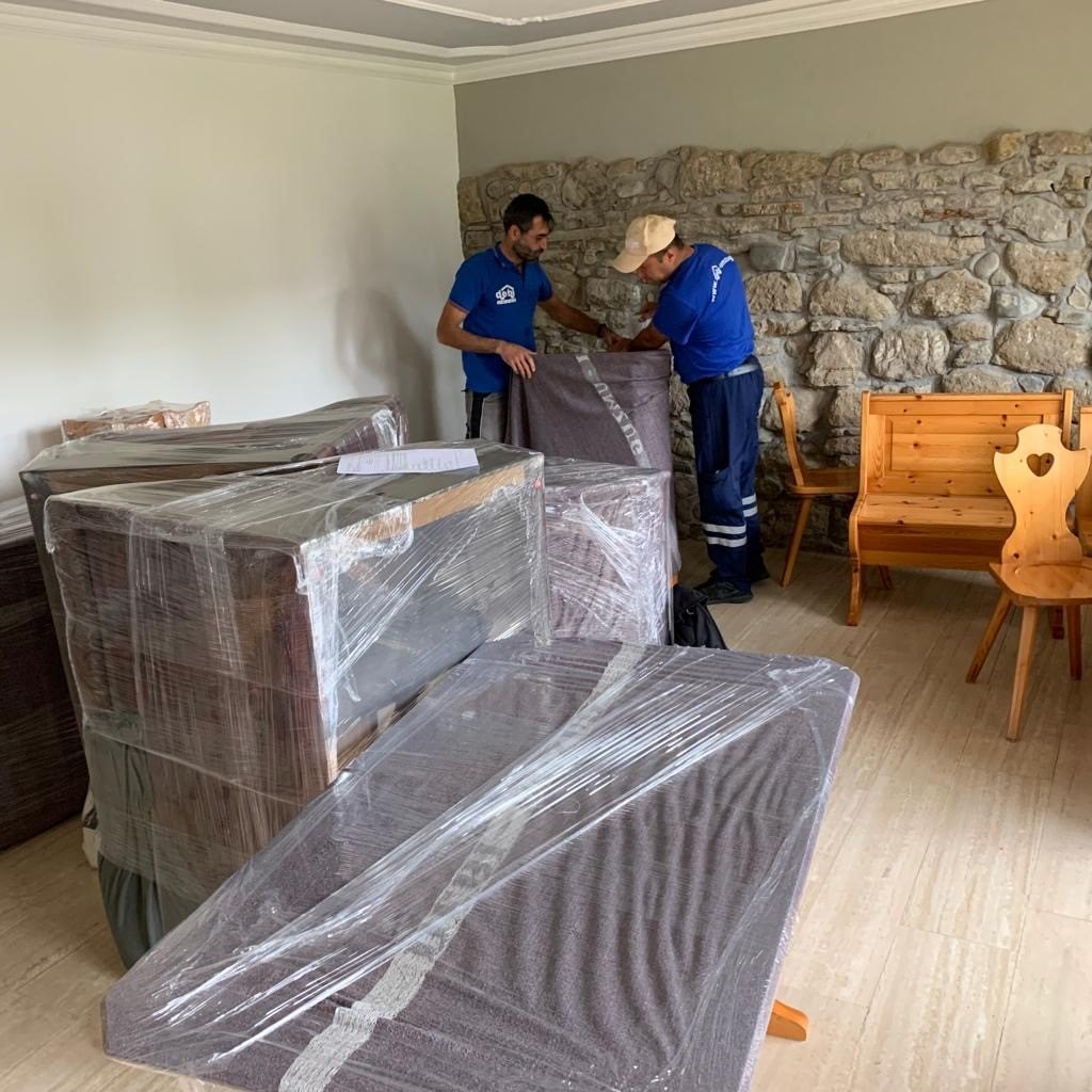 Zwei Mitarbeitende von Debi Umzug verpacken Möbel in Schutzfolie